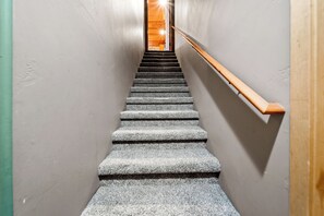 Eine Holztreppe mit Geländer führt zu einer Holztür oben.