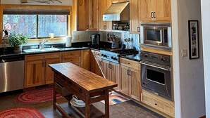 Une cuisine avec des meubles en bois, un four encastré et un coin repas avec un banc.