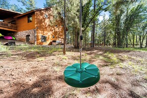 A wooden cabin with a stone foundation, surrounded by a forest. - Trade the Heat for the Pines: Pinetop Family Cabin, Kayaks & Cool Nights (Pinetop)