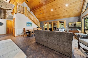 A spacious living area with a wooden staircase, a fireplace, and a television. - Trade the Heat for the Pines: Pinetop Family Cabin, Kayaks & Cool Nights (Pinetop)