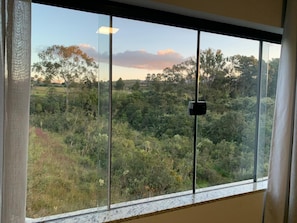 A window with a view of a forested landscape. - Vista Imperial Diamantina - Comfort and Nature in Harmony. (Diamantina)