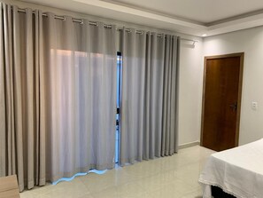 Une pièce avec un lit, une porte en bois et un rideau à moitié tiré.