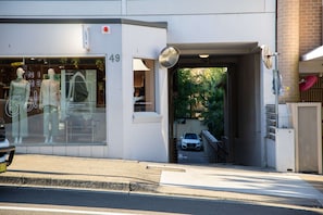 A storefront with mannequins displaying clothing, a visible entrance, and a parked car in the background. - Bondi Studio, Private Balcony | 2 Min Walk to Beach, Full Kitchen & AC (Bondi Beach)