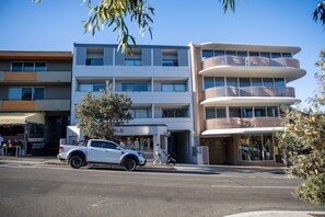 A multi-story building with a ground-level retail space and upper residential units. - Bondi Beach Studio | Private Balcony & Kitchen (Bondi Beach)