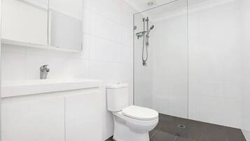 Une salle de bain moderne équipée de toilettes, d’un lavabo et d’une douche.