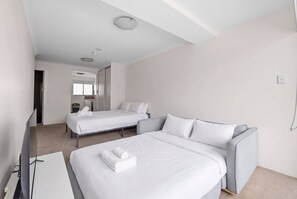 A hotel room with two beds, a sofa, a desk, and a bathroom visible in the background. - Bondi Studio, Private Balcony | 2 Min Walk to Beach, Full Kitchen & AC (Bondi Beach)