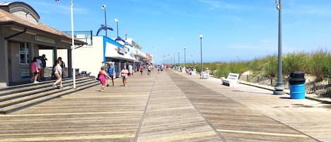 A boardwalk with shops and a beach in the background.