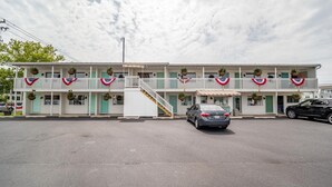 A two-story motel with a central staircase, balconies with railings, and a covered front porch. - Cottage Queen One-Bedroom | Ocean Glass | Steps to Sand | Free WiFi (Rehoboth Beach)