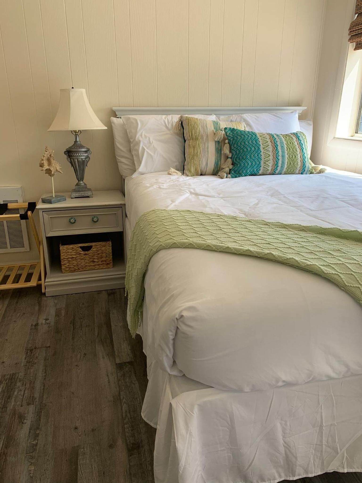 A bedroom with a bed, a nightstand, a lamp, and a window with curtains.