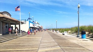 A boardwalk with shops, a beach, and a clear sky.