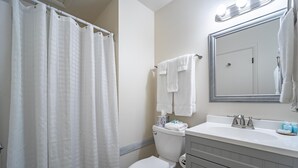 Een badkamer met toilet, wastafel, spiegel en douchegordijn.