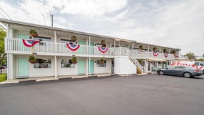 Ein Motel mit mehreren Balkonen, einer überdachten Veranda und einem geparkten Auto davor.