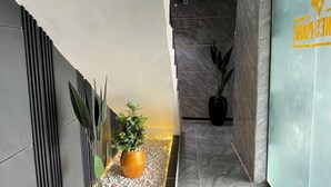 Un pasillo moderno con piso de mármol, una maceta decorativa roja y plantas en macetas.