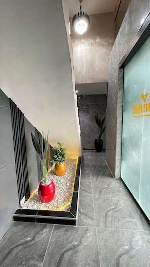 A modern hallway with a marble floor, a red decorative planter, and potted plants. - X-ones place command  (Lagos)