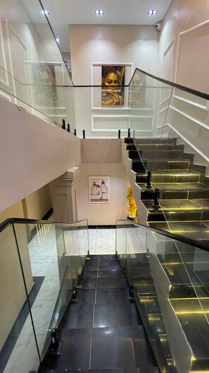 A modern interior with a glass staircase, marble flooring, and artwork on the walls. - X-ones place command  (Lagos)