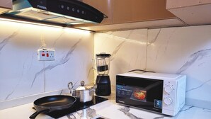 Una cocina con estufa, sartén, licuadora y microondas.