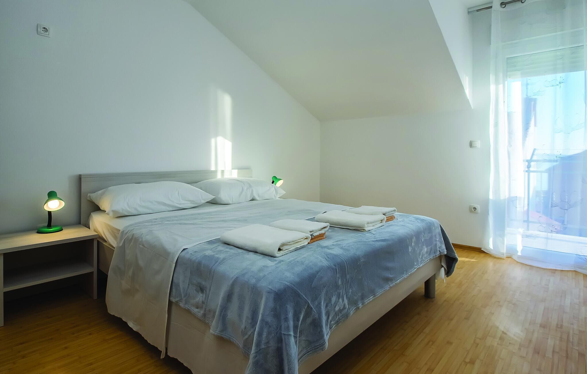 A bedroom with a bed, a nightstand, a lamp, and a window with curtains.