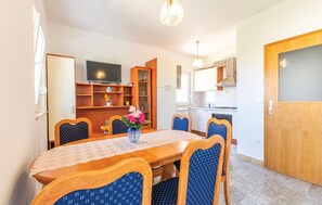 A dining area with a table, chairs, a TV, and a kitchen in the background. - Apartment in Podstrana (256) (Podstrana)