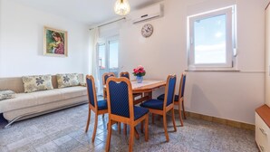 Un coin repas avec une table ronde en bois, des chaises à revêtement bleu, un vase de fleurs, une horloge et un tableau accroché au mur.