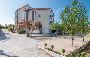A multi-story building with a tiled roof, a driveway, and a small parking area. - Apartment in Podstrana (256) (Podstrana)