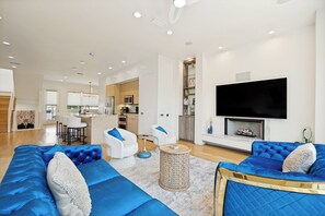 A modern living room with a large sofa, a television, and a fireplace. - The Q: Dallas - Spacious 3 bedroom Dallas townhome w. Rooftop Sauna Gym DT (Dallas)