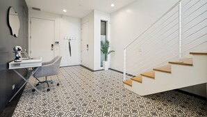Ein modernes Interieur mit einer Treppe, einem Schreibtisch mit Stuhl und einem gestreiften Boden.