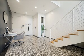 Ein modernes Interieur mit einer Treppe, einem Schreibtisch mit Stuhl und einem gestreiften Boden.