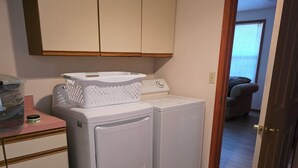 Ett tvättrum med tvättmaskin, torktumlare och en korg på bänken.