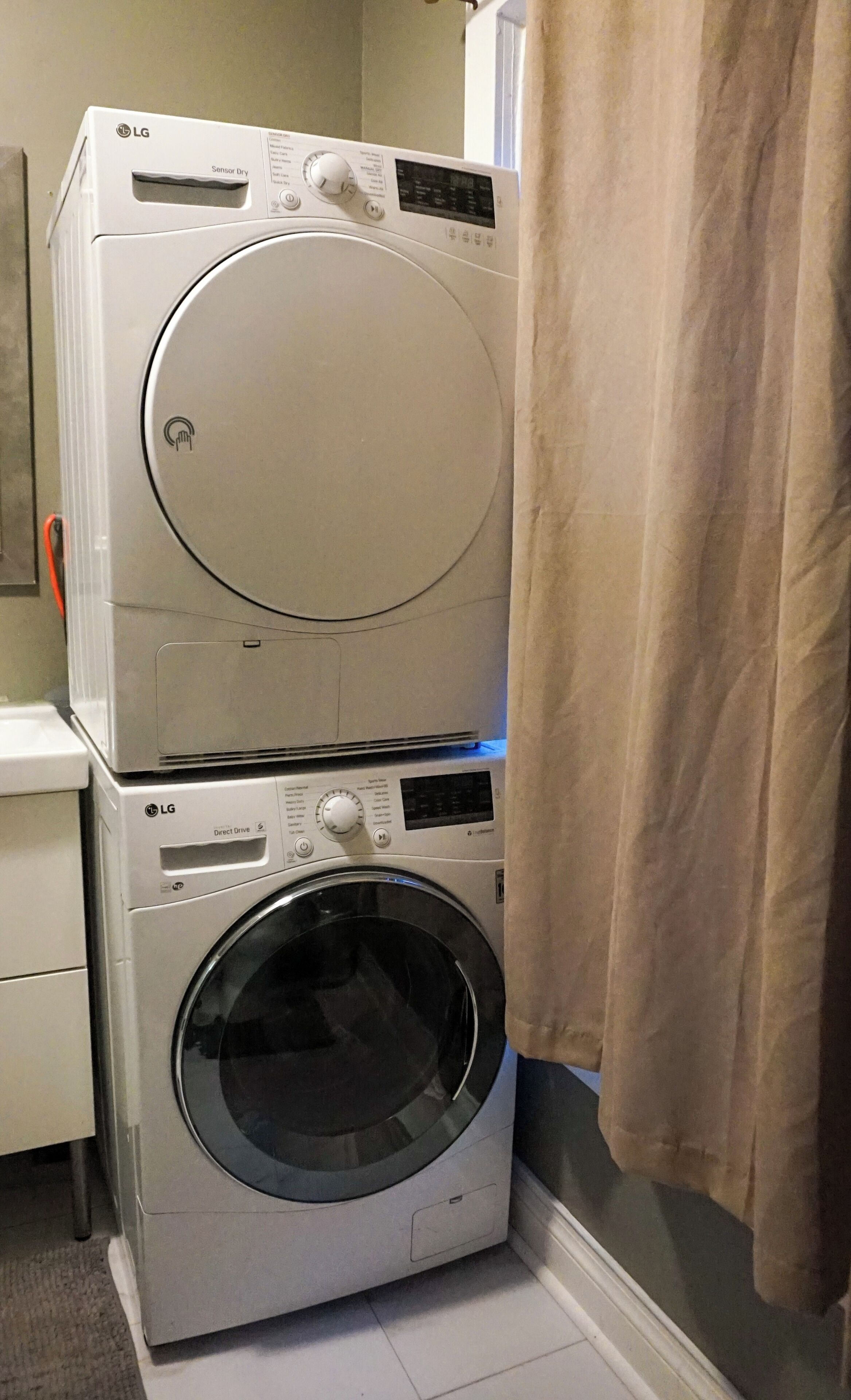 A stacked washer and dryer in a room with a curtain.
