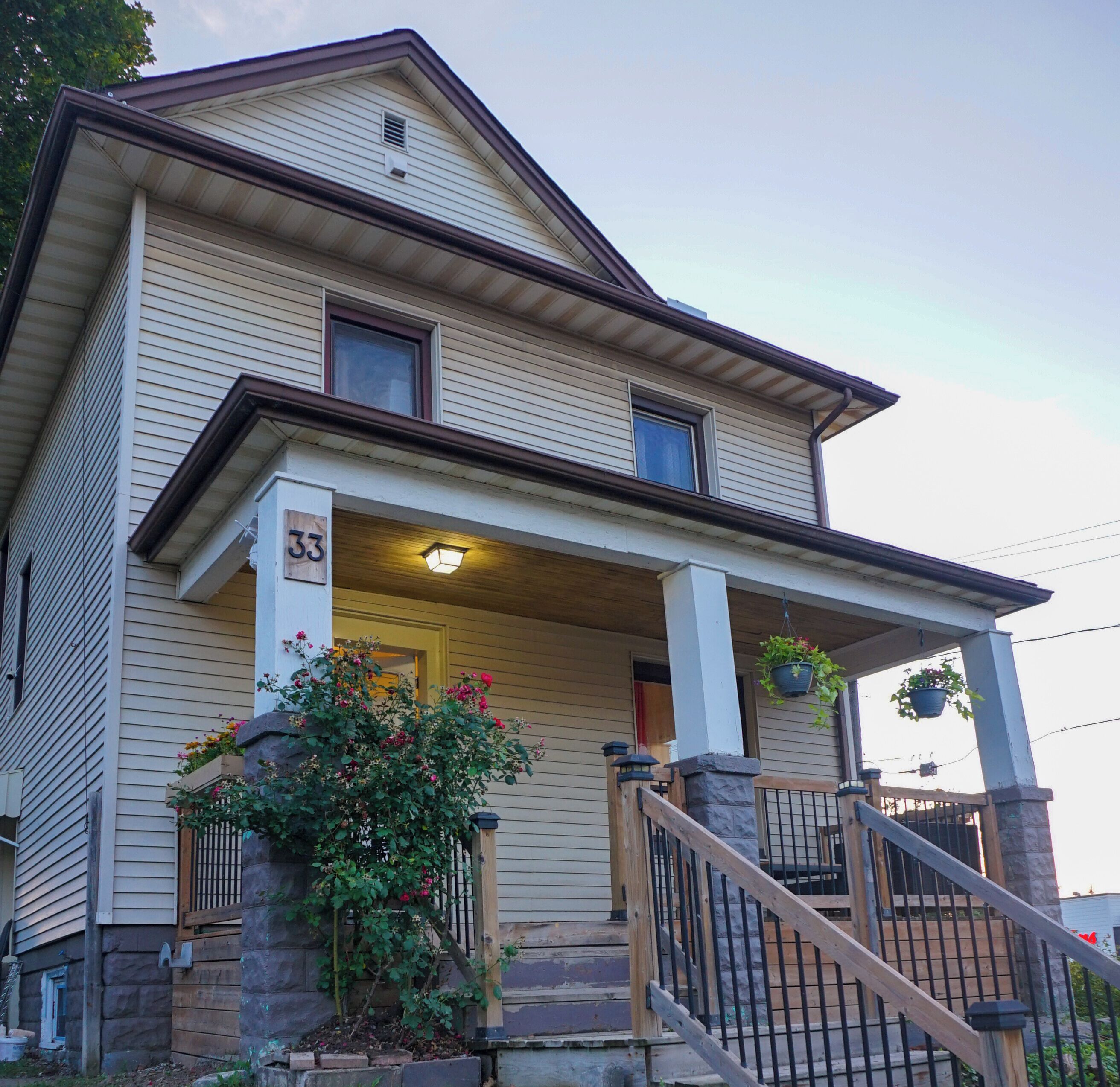 A two-story house with a porch, a number '33' sign, and a staircase leading to the entrance.