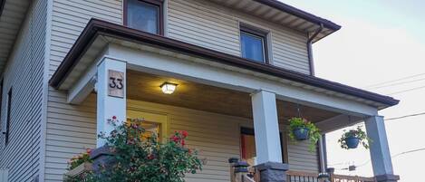 A two-story house with a porch, a number '33' sign, and a staircase leading to the entrance.