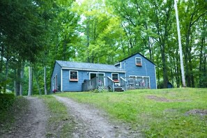 Una casa a due piani con un portico, immersa tra gli alberi.