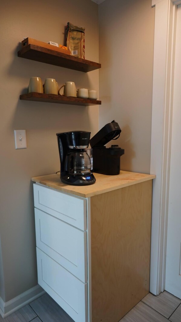 A compact kitchen with a coffee maker, a shelf with mugs, and a bag of coffee. - Big Blue at Little Long Lake (Harrison)