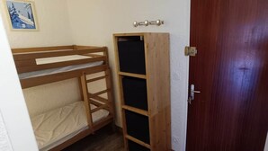 Huone, jossa on kerrossängyt, puinen vaatekaappi ja ovi.