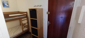 Ein Zimmer mit Etagenbetten, einem Holzschrank und einer Tür.