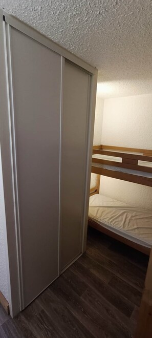 A room with a bunk bed, a sliding door, and wooden flooring. - Le nid des 2 Alpes - Pied de pistes - Hypercentre (Les Deux Alpes)