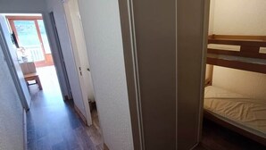 Kapea käytävä johtaa huoneeseen, jossa on kerrossänky.
