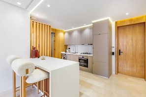 A modern kitchen with a central island, built-in appliances, and a wooden accent wall. - Stunning apartment with a terrace in Gueliz-Majorelle (Marrakech)