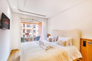 A hotel room with a bed, a TV, a balcony with a view of buildings, and a wooden panel wall. - Stunning apartment with a terrace in Gueliz-Majorelle (Marrakech)