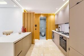 A modern kitchen with a central island, built-in appliances, and a wooden partition. - Stunning apartment with a terrace in Gueliz-Majorelle (Marrakech)