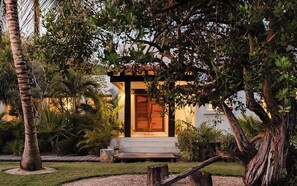 Un kiosque doté d’une porte en bois, entouré d’une végétation luxuriante et de palmiers.