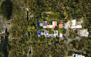 An aerial view of a resort with multiple buildings, solar panels, and a natural forested area. - Luxury Family Villa on Yalku Lagoon · Private Cenote · Akumal (Tulum)