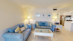 Ein Wohnzimmer mit zwei Sofas, einem Couchtisch und einer Küchenzeile inklusive Kühlschrank und Mikrowelle.
