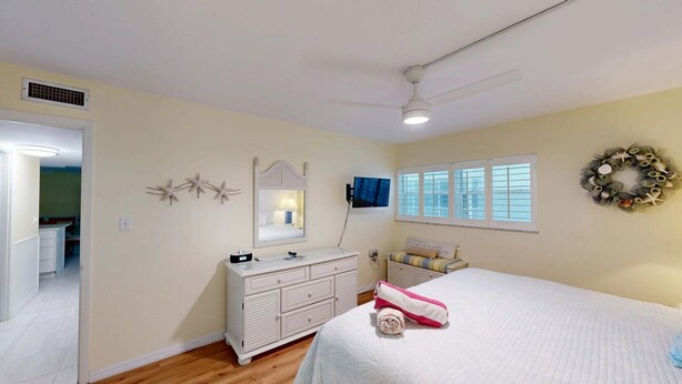 Ein Schlafzimmer mit Bett, Kommode, Schminktisch und Deckenventilator.