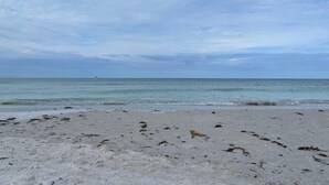 Ein Strand mit blauem Himmel und ruhigem Meer.