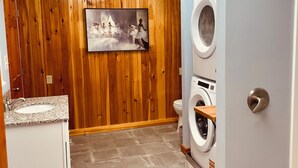 Una lavanderia con pareti di legno, un lavandino e due lavatrici.