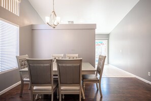 A dining area with a table and chairs, a chandelier, and a view of the outside. - Cozy Cool 3 Bedrooms Home W~Pool (North Las Vegas)