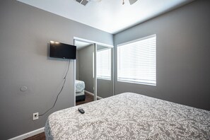 A bedroom with a bed, a television mounted on the wall, and a window with blinds. - Cozy Cool 3 Bedrooms Home W~Pool (North Las Vegas)