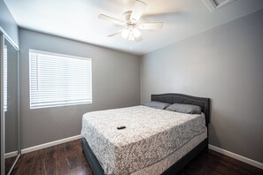 A bedroom with a bed, a ceiling fan, a window with blinds, and a door. - Cozy Cool 3 Bedrooms Home W~Pool (North Las Vegas)