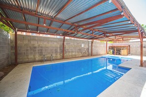 En swimmingpool med et metal tag og en murstensvæg.